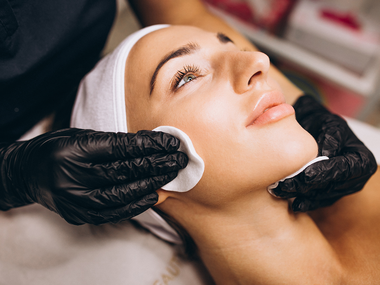 Cosmetologist cleaning face of a woman in a beauty salon